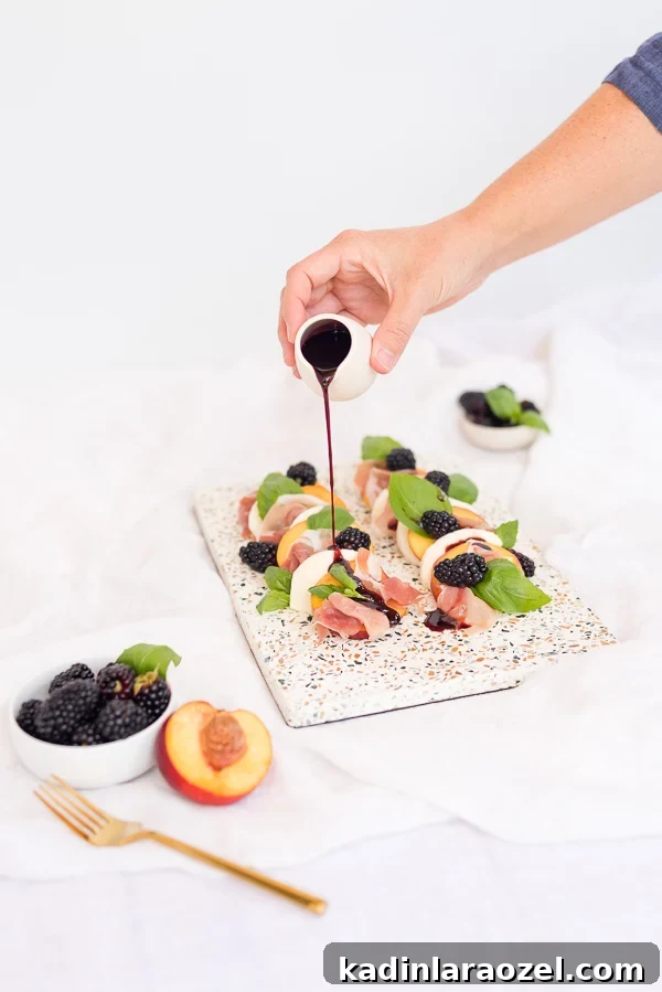 Pouring blackberry balsamic dressing onto a peach and prosciutto caprese salad.