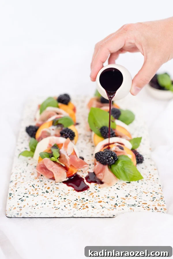 Pouring blackberry balsamic reduction onto unique caprese salad.