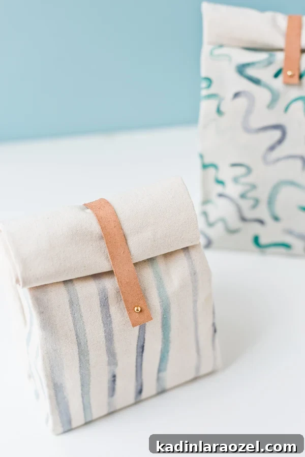 two canvas lunch bags sitting on a white counter, with leather closures