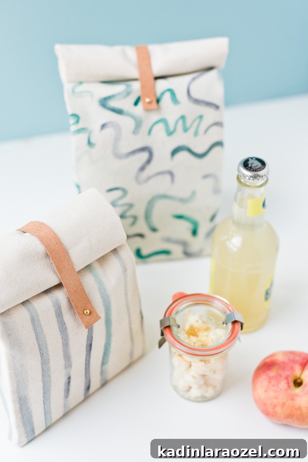 two lunch bags with painted designs on them, sitting on table with food and drinks