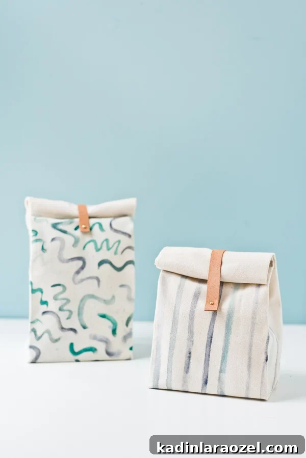 Two canvas lunch bags sitting on white table with blue background