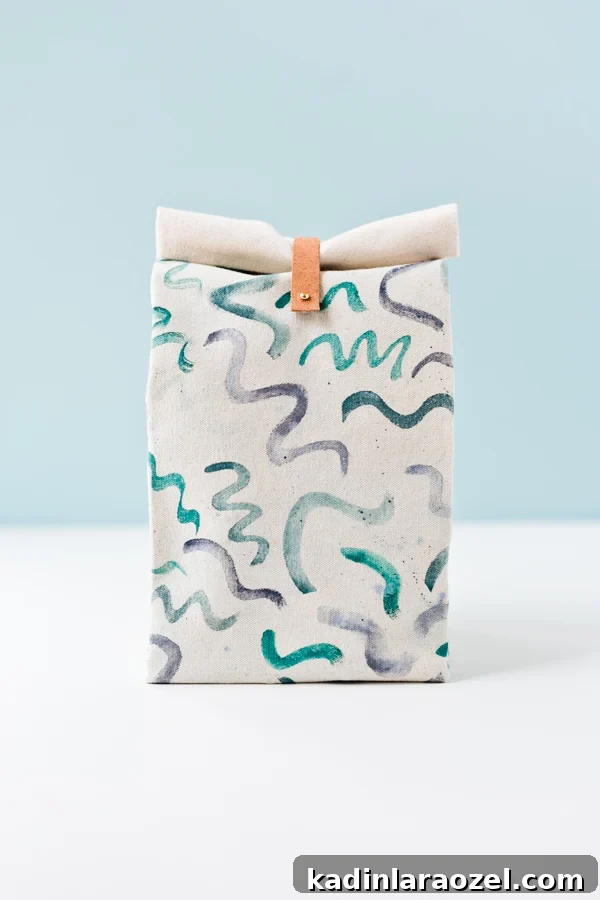 Canvas lunch bag sitting on table, with painted squiggle lines in various blues and greens