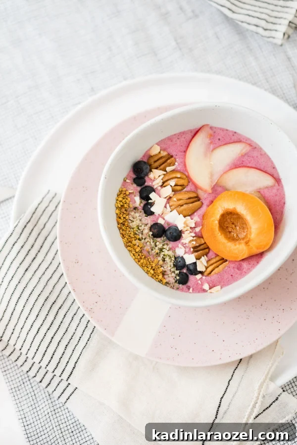 2-Ingredient Smoothie Bowls You Can Make in Minutes 2 Pink smoothie bowl with fruit and nuts lined up in bowl.