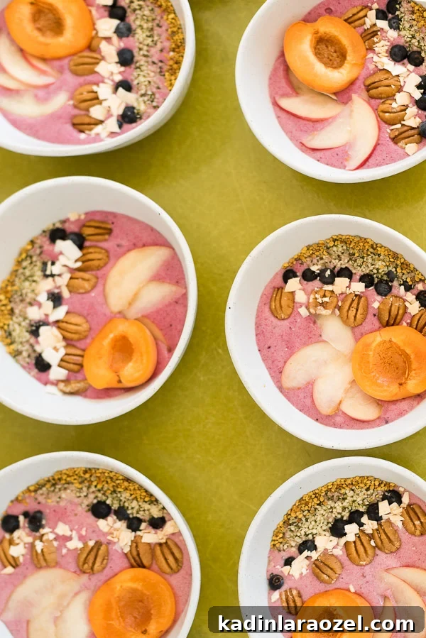 2-Ingredient Smoothie Bowls You Can Make in Minutes 5 rows of smoothie bowls with fruit and nuts lined up in each bowl, on a green tray.