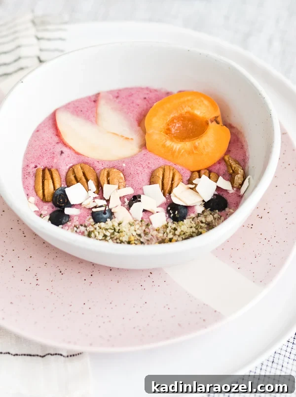 2-Ingredient Smoothie Bowls You Can Make in Minutes 7 Close-up pink smoothie bowl with sliced fruit and chopped nuts on top.