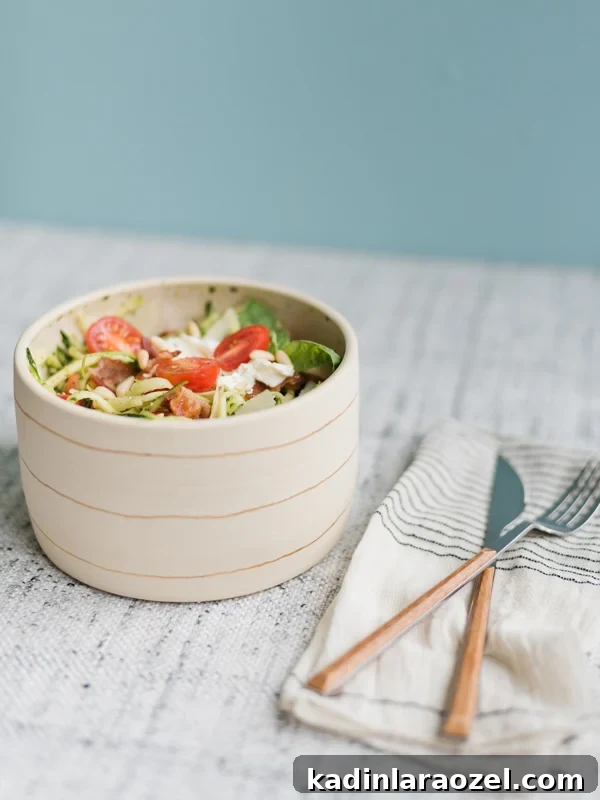 Image of a zucchini noodle salad with tomatoes and cheese on top.