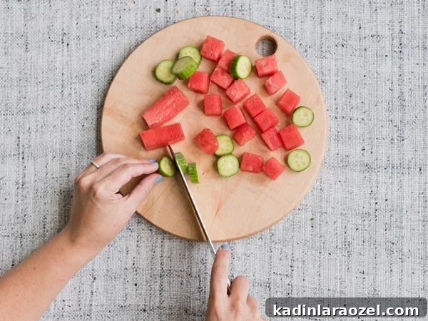 Chop watermelon and cucumbers for a fresh summer salad recipe. 
