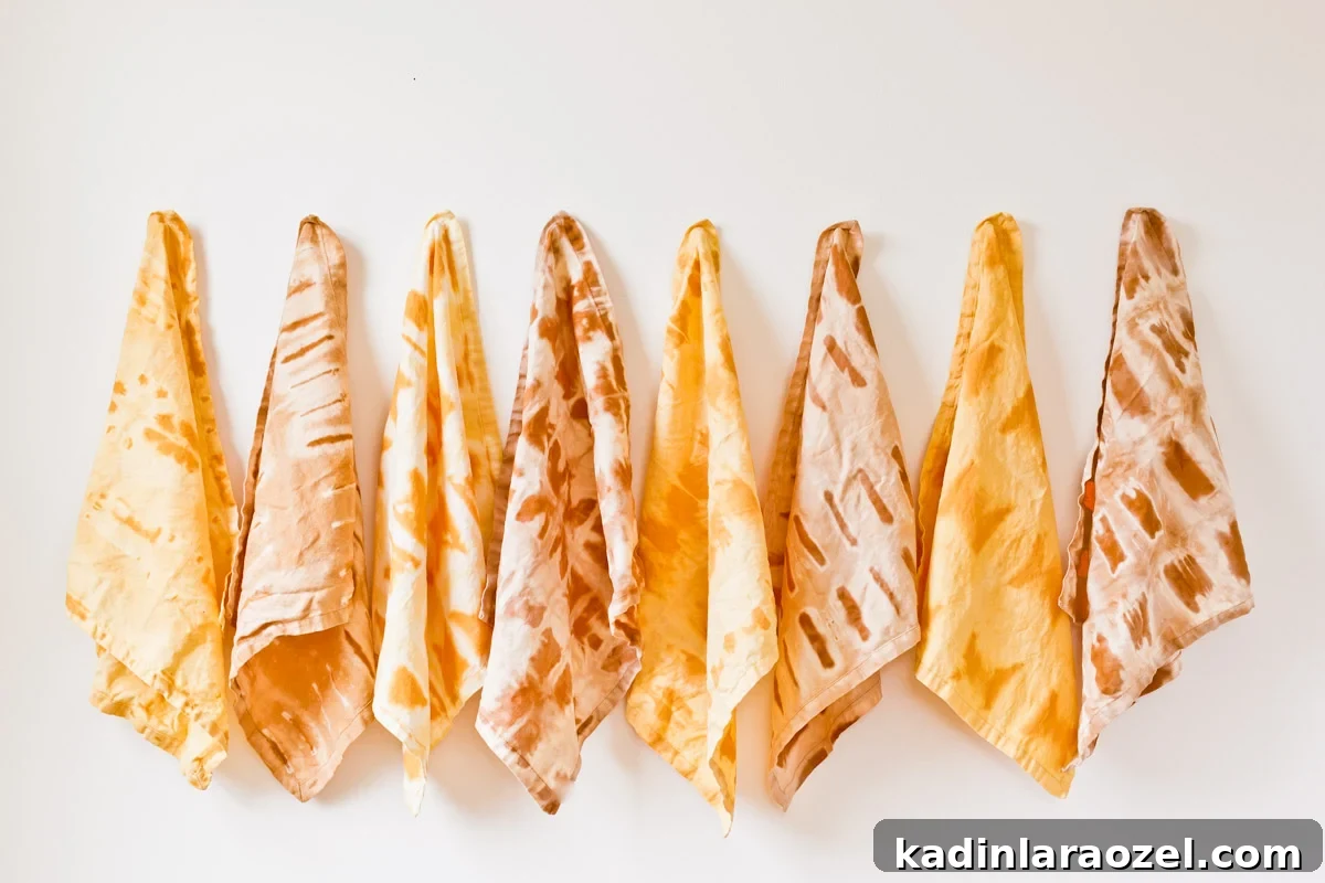 Shibori tie dye napkins in earth tones, lined up, hanging on a white wall.