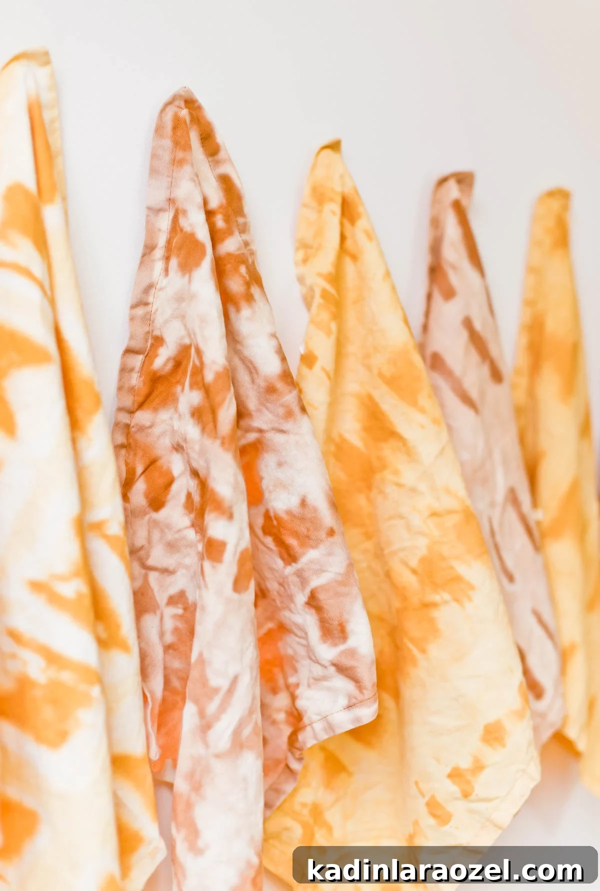Earthy tone shibori and tie dye pattern napkins hanging on a white wall.