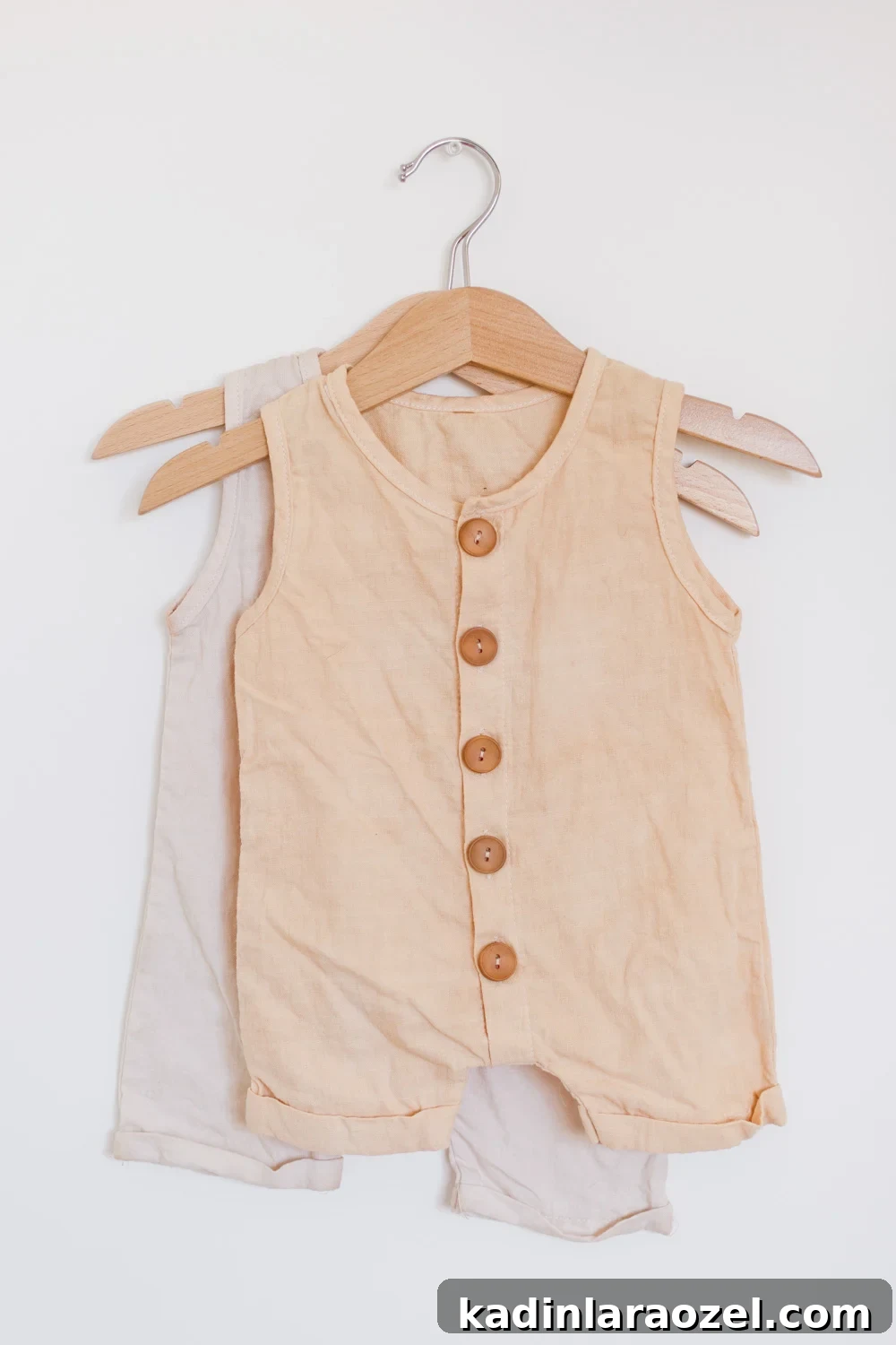 Natural Fabric Dyeing: How to Dye Clothes with Plant-Based Colors 9 Neutral baby clothes, hanging from a hanger on a white wall