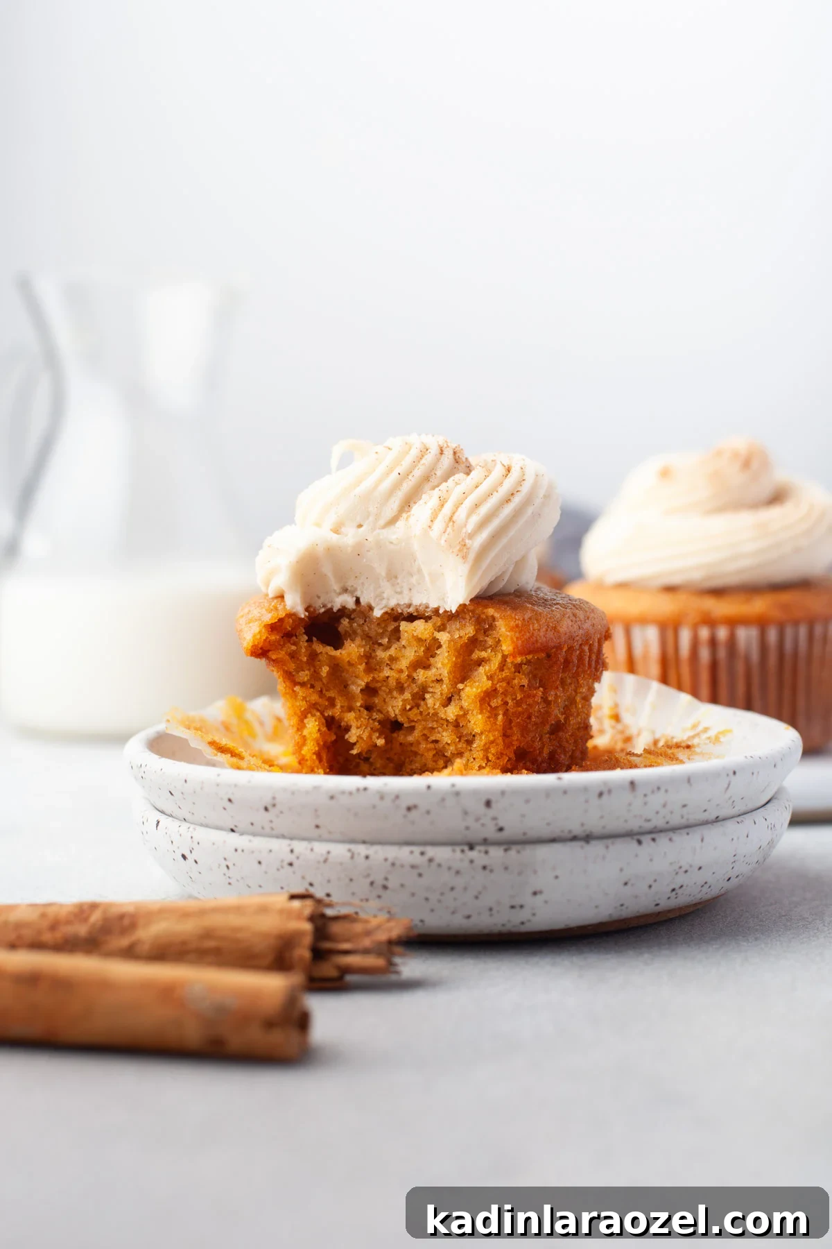 11 Irresistible Fall Recipes You’ll Crave This Season 5 pumpkin cream cheese cupcakes on a plate with a bit out of it