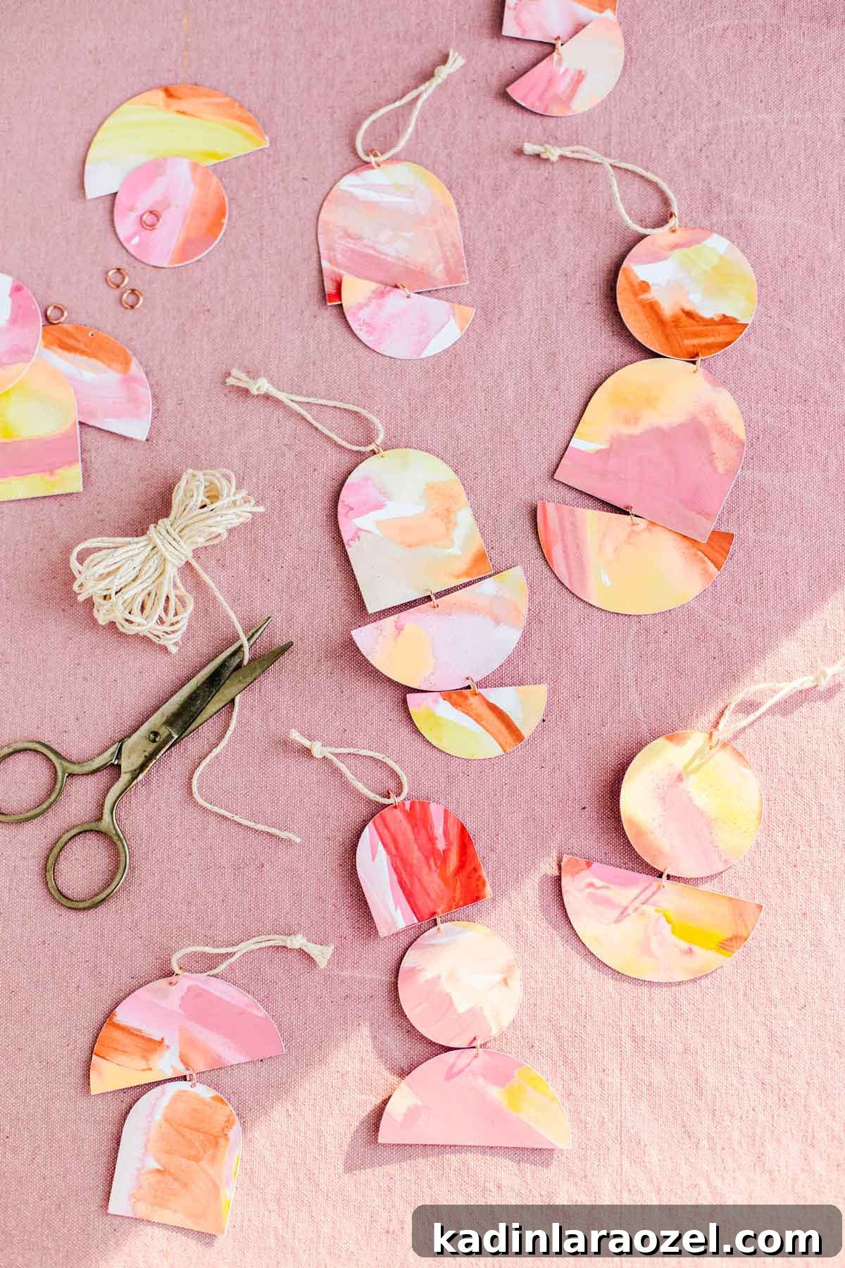 Painted paper ornaments in various geometric shapes stacked on top of one another to resemble jewelry