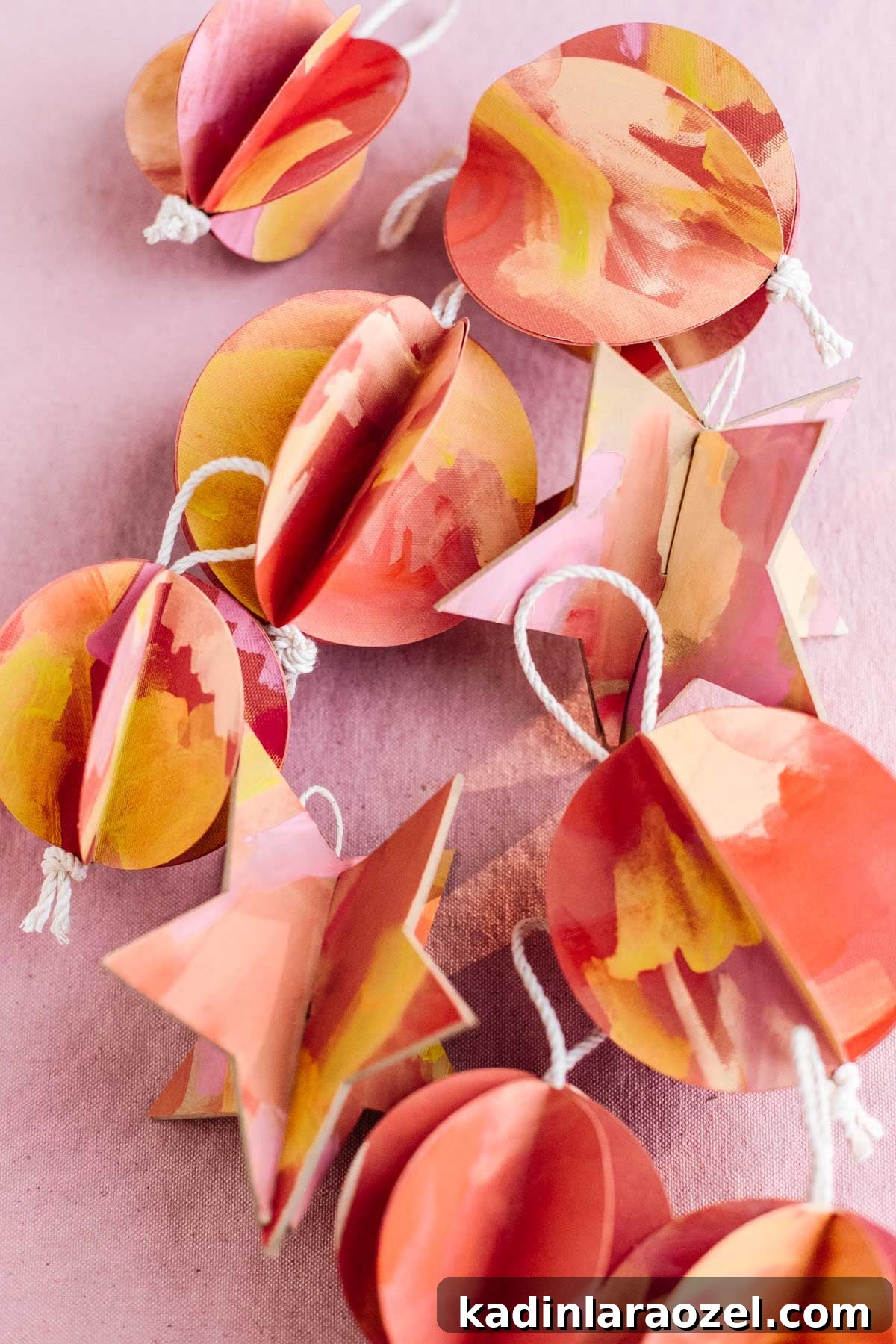 Paper Christmas ornaments in star and ball shapes, painted red, pink, orange, and yellow