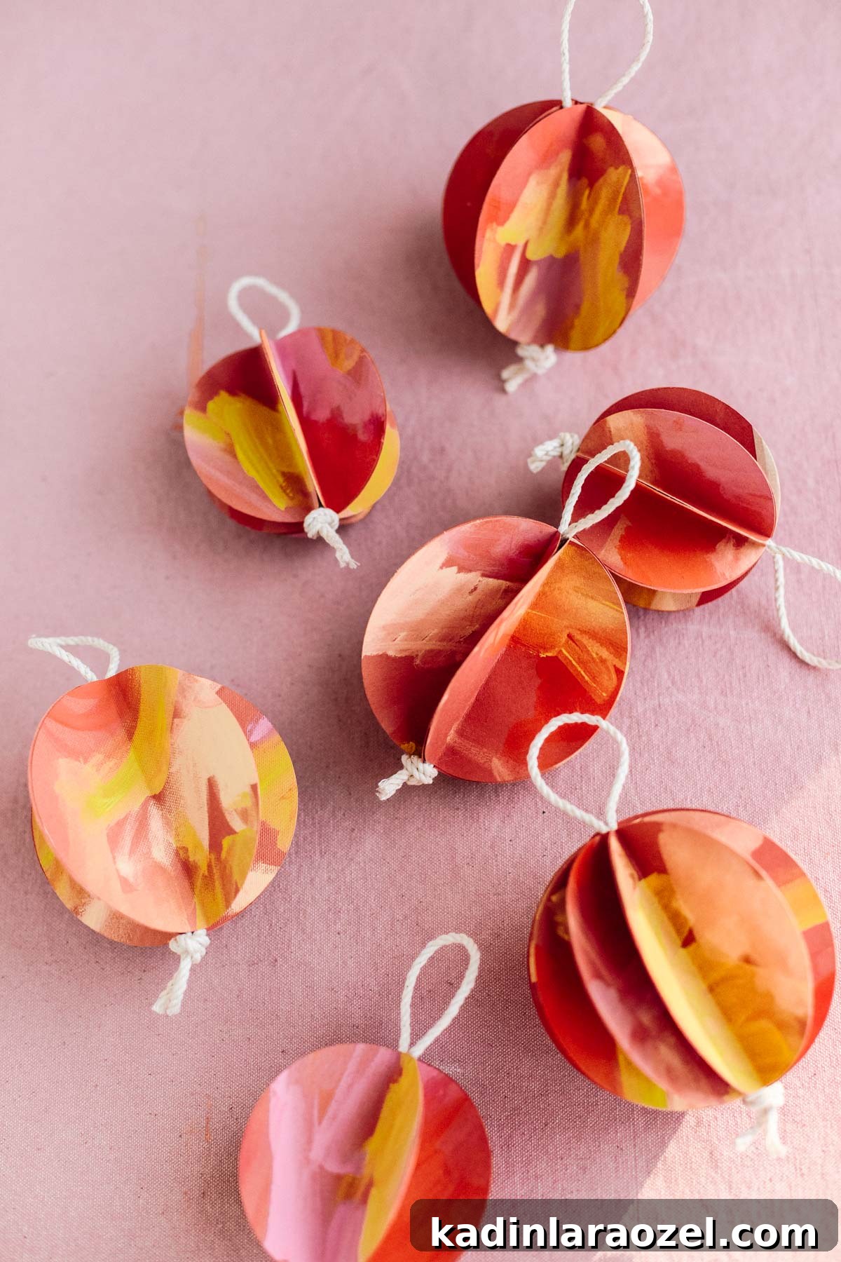 Three-dimensional ball ornaments on pink backdrop with string loops at the top