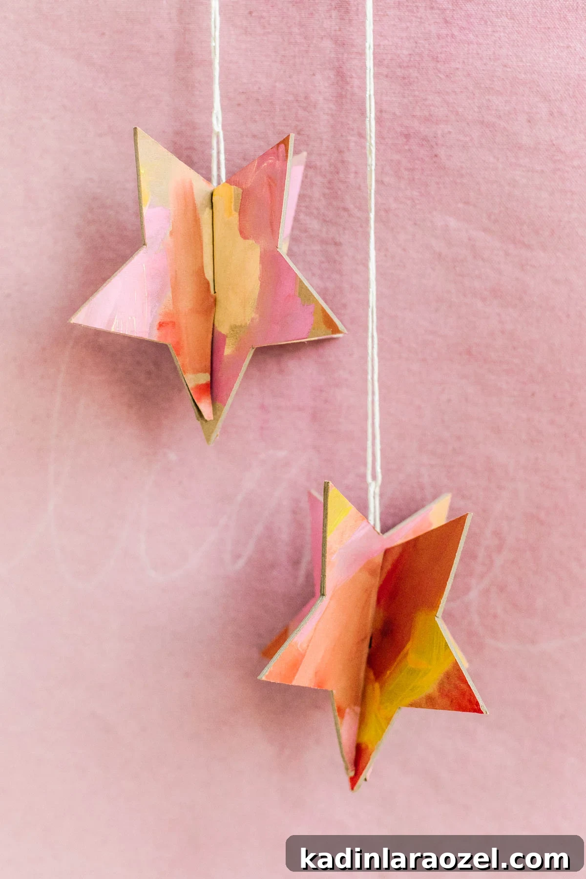 3D stars, painted warm colors and hanging in front of a light pink backdrop