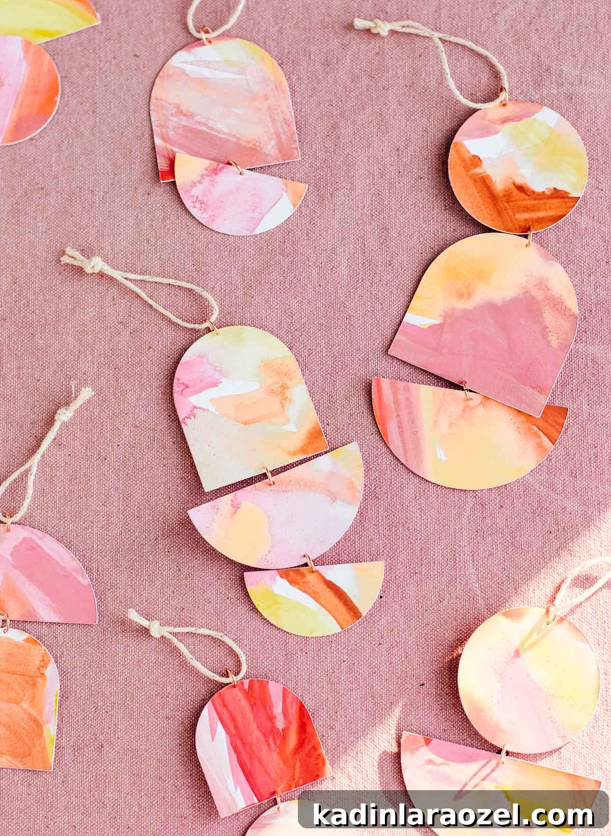 Geometric ornaments painted in warm colors with copper rings hooking them together.