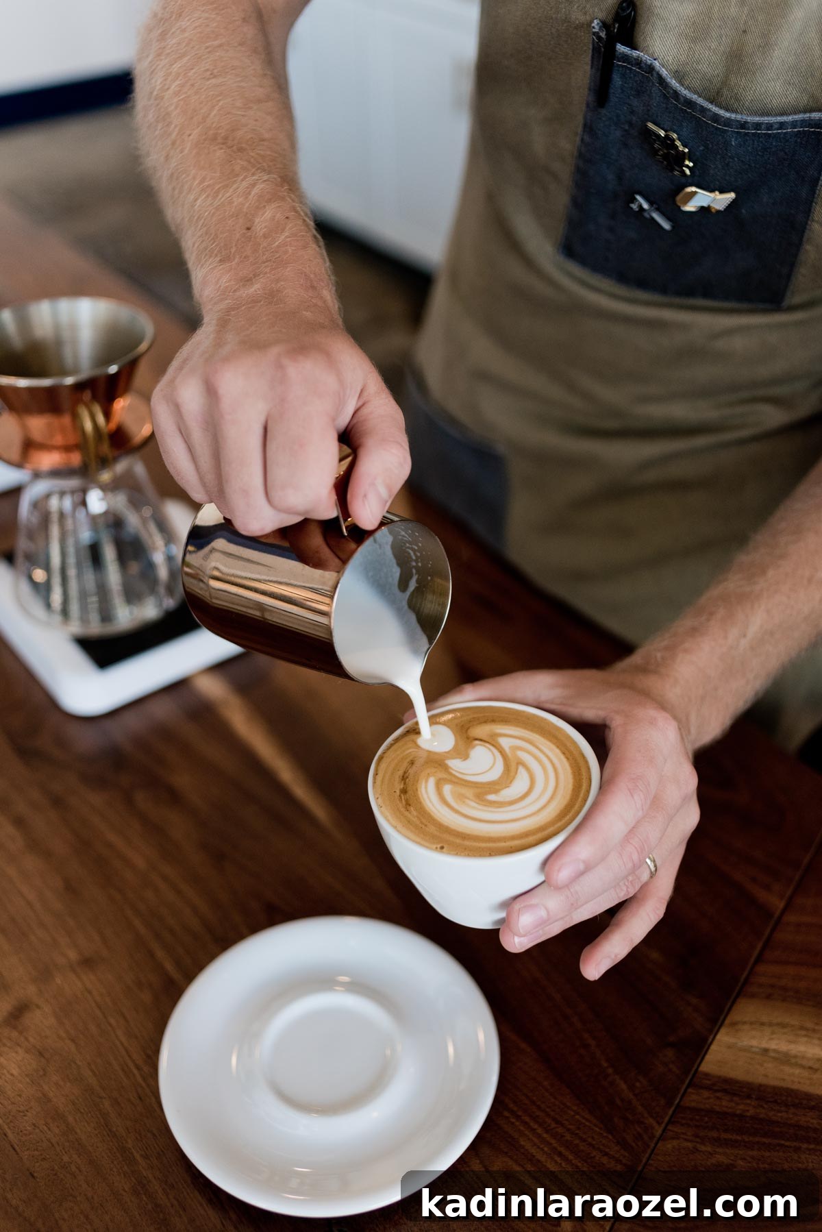 man pouring frothed milk over a cappuccino in a leaf design