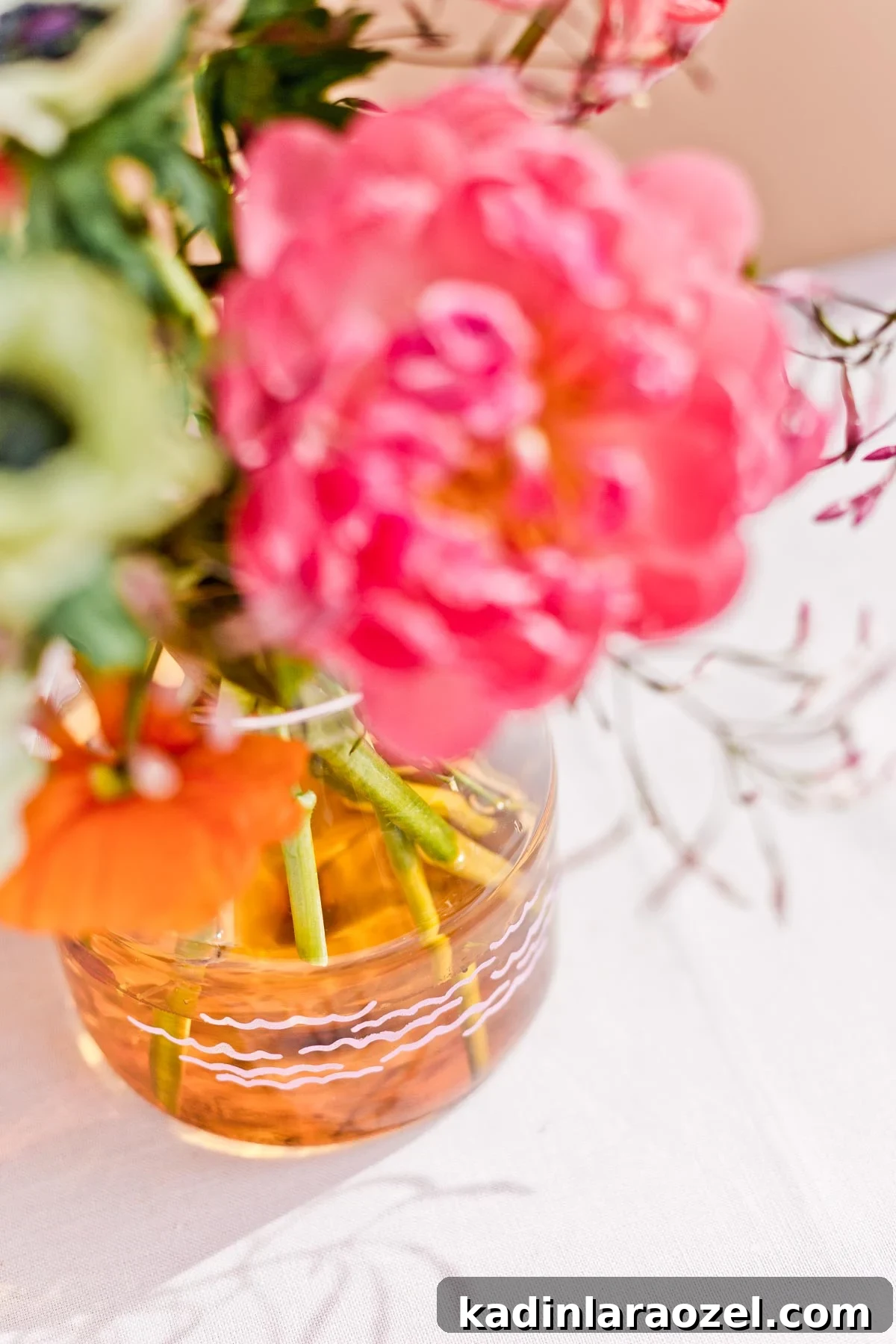 Orange glass vase holding colorful fresh flowers like peonies