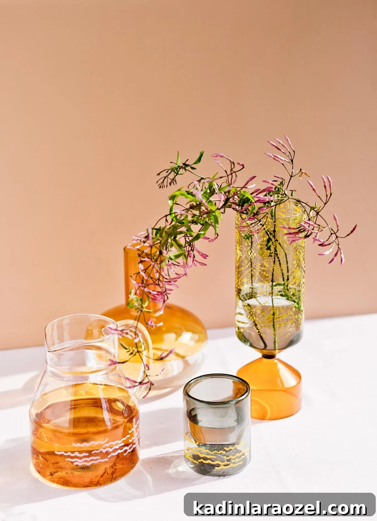Glasses vases with painted stencil designs on muted orange background with the sun shining through