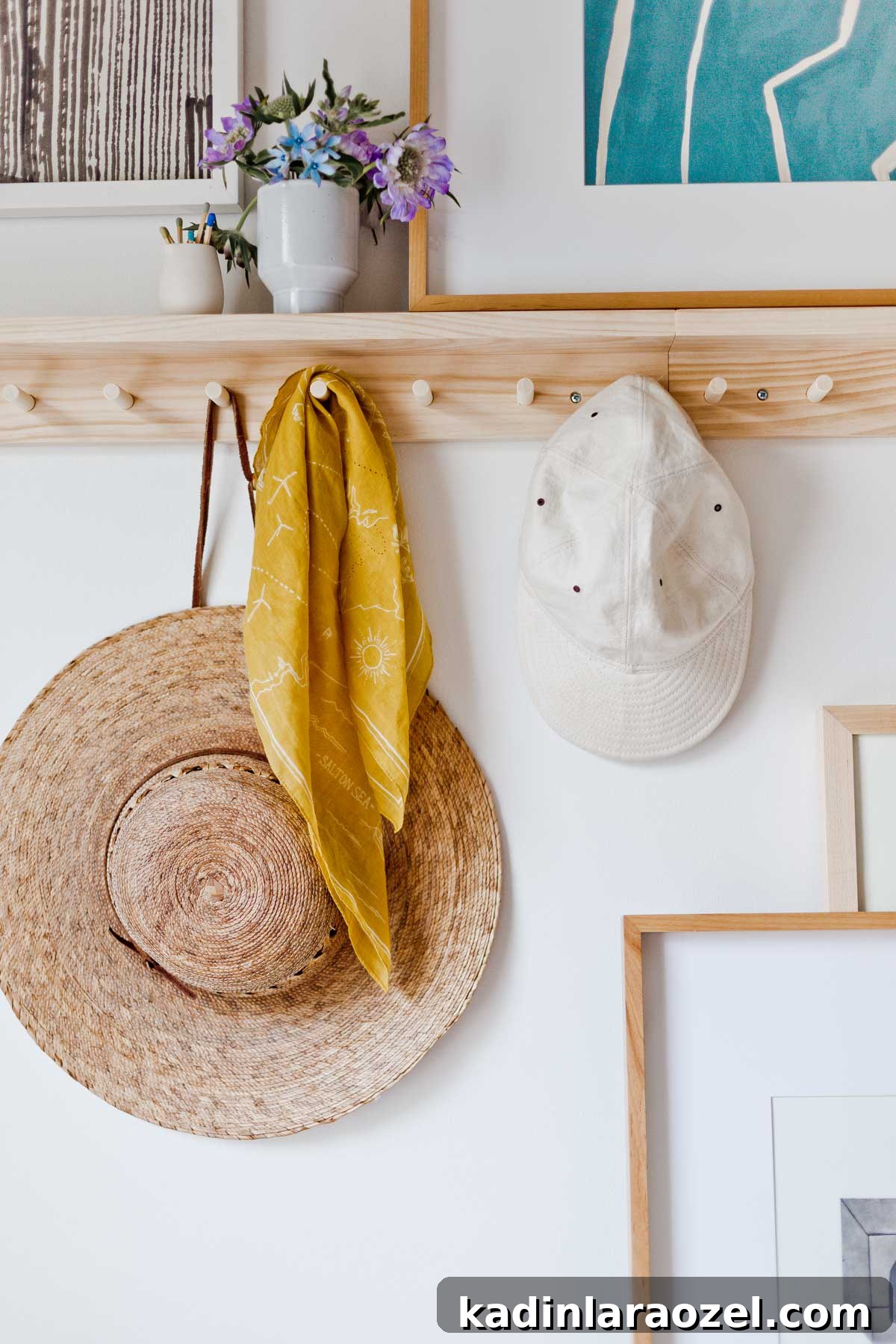 Wooden peg rail on wall, with hats hanging down and artwork resting on the shelf above