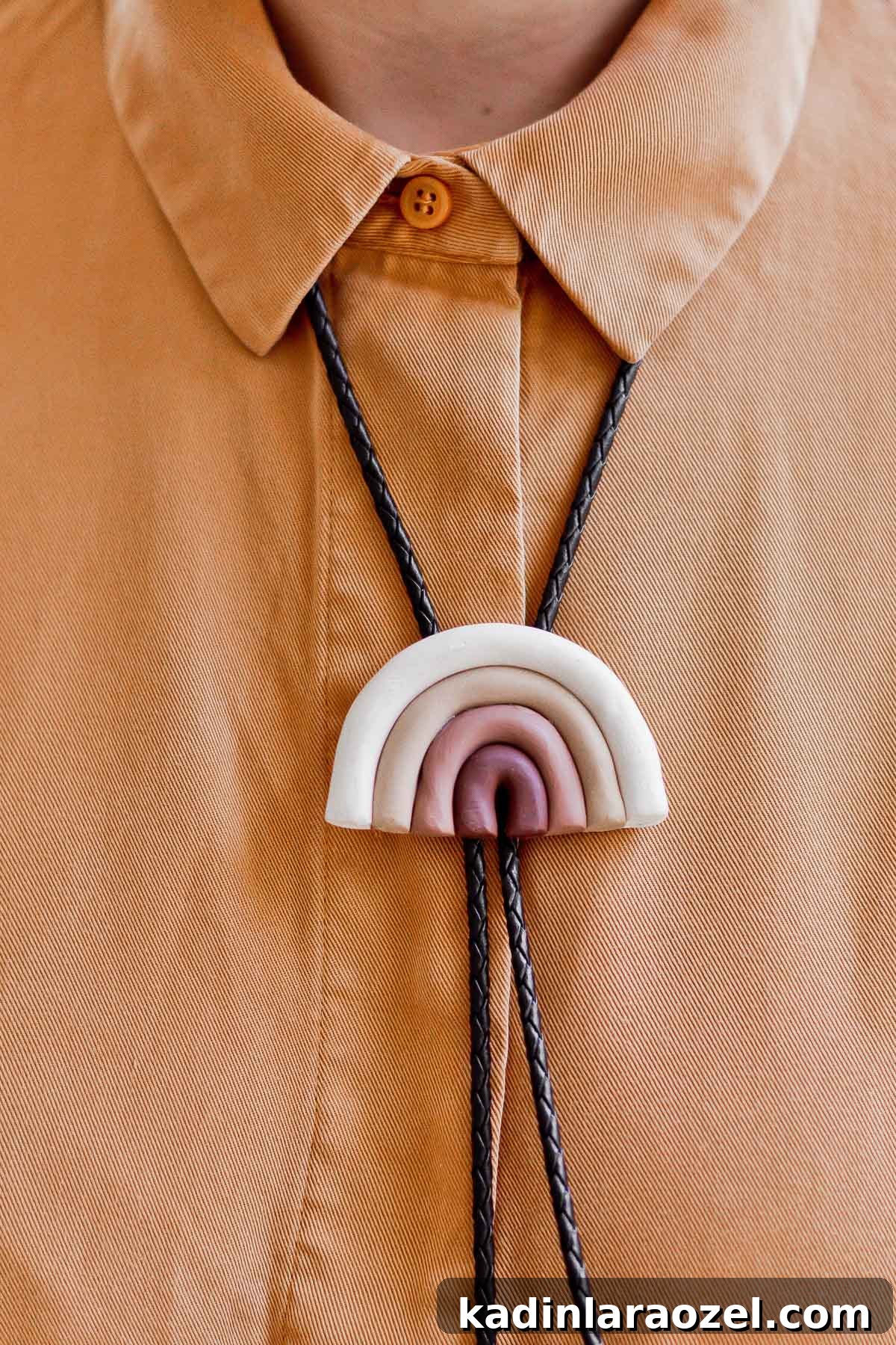 Detail photo of rainbow bolo tie made of clay, in earth tones.