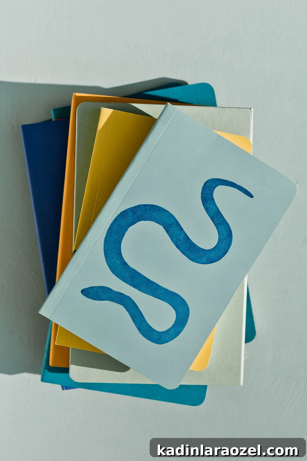 3 Stylish Back-to-School DIY Projects That Impress 12 Stacked set of notebooks in bold colors, with a snake design on top