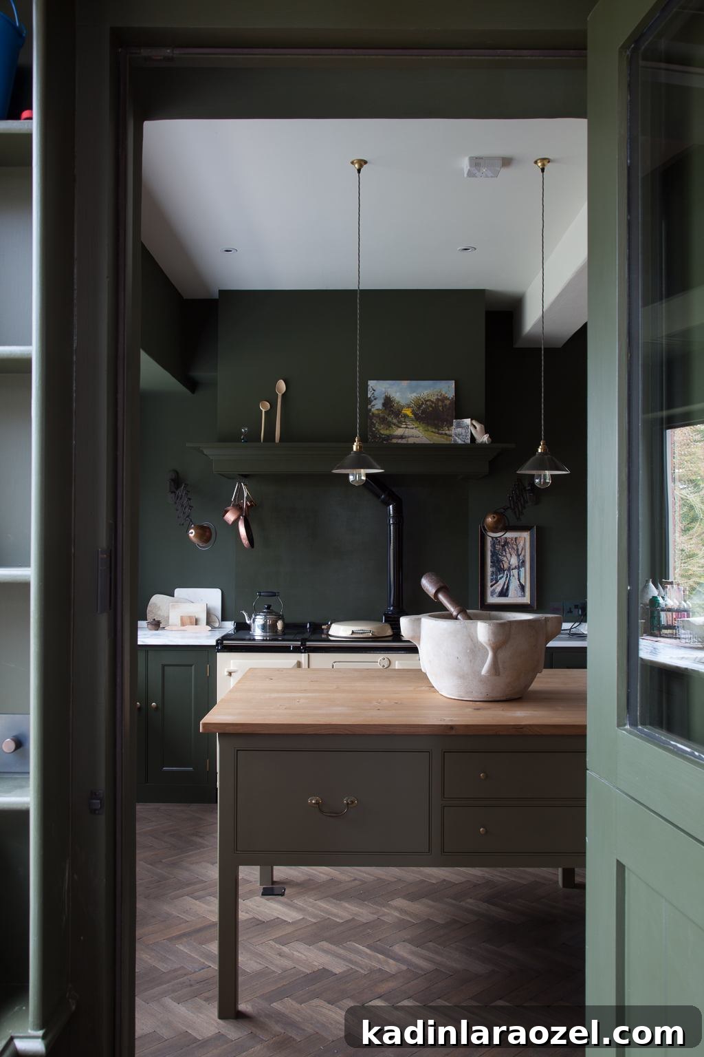 Moody Green Interiors: 12 Stylish Ways to Use the Color 2 Moody green kitchen with wooden island and herringbone floors.