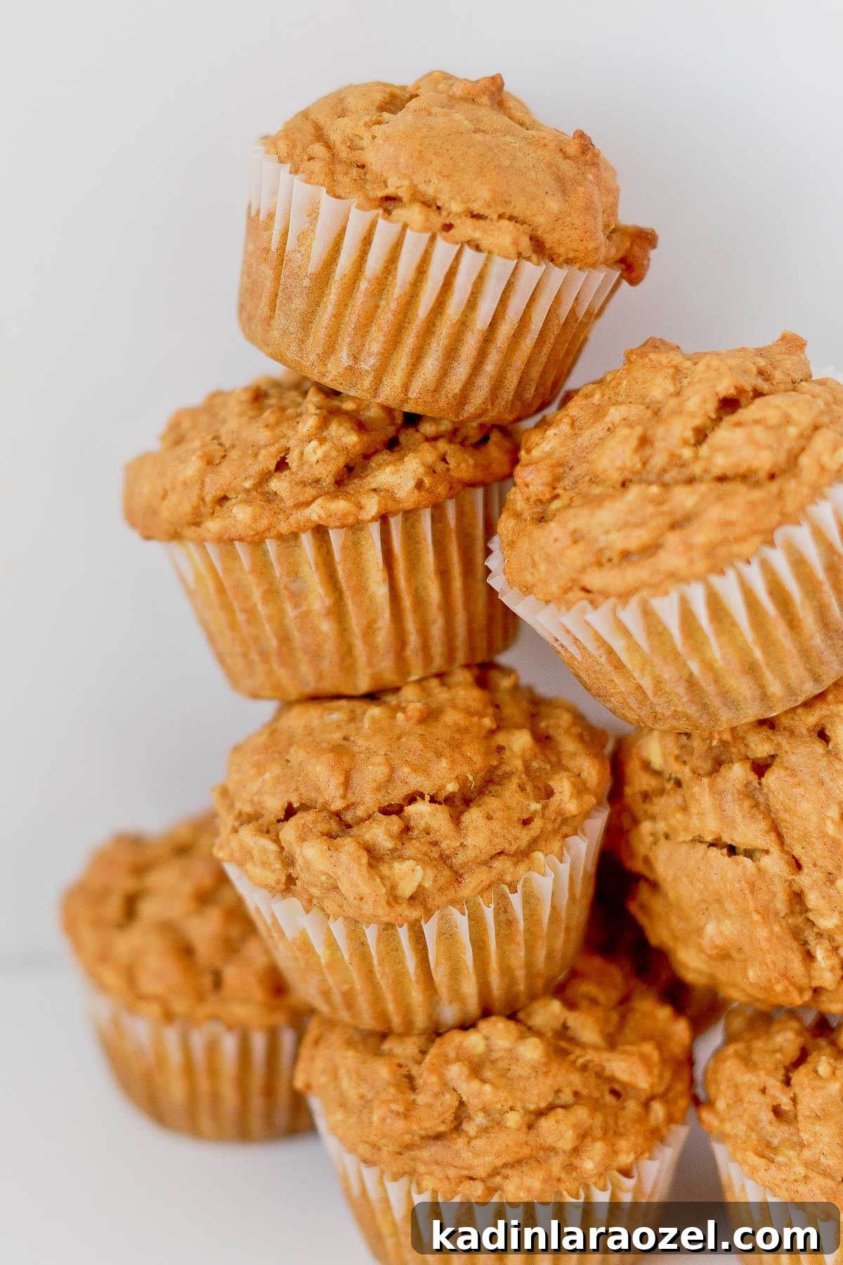 Simple Delicious Pumpkin Muffins Recipe You’ll Love 3 Pumpkin oat muffins stacked on top of each other, close up.