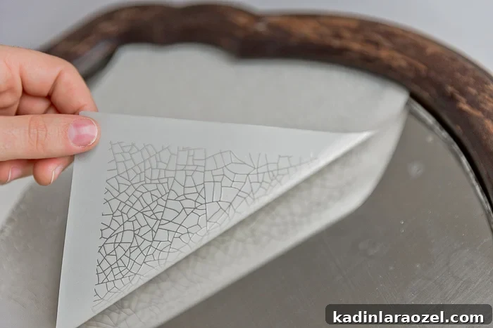 Attaching stencil to the mirror to create an antique pattern.