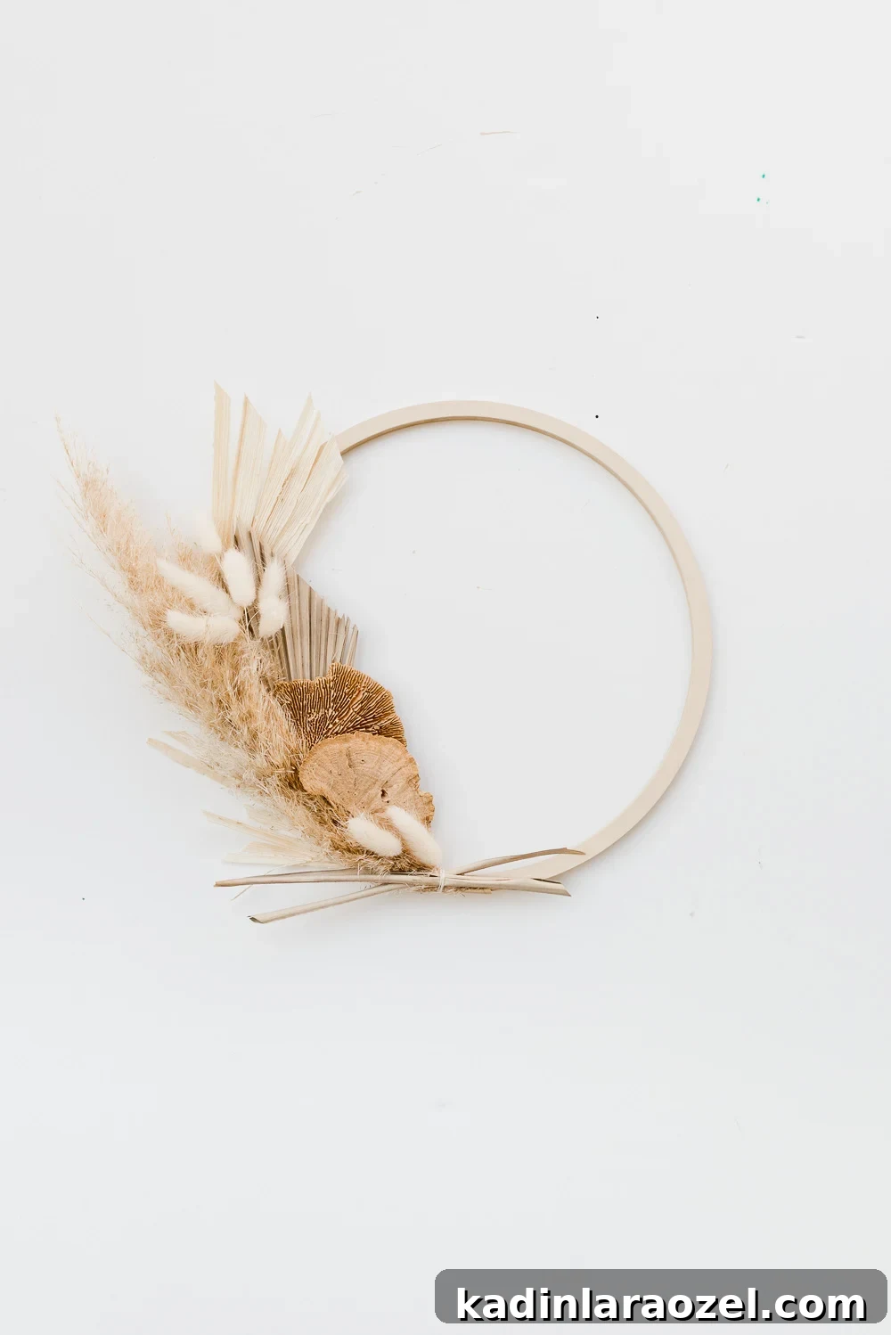An asymmetrical fall wreath made of pampas grass, wheat, and palm leaves.