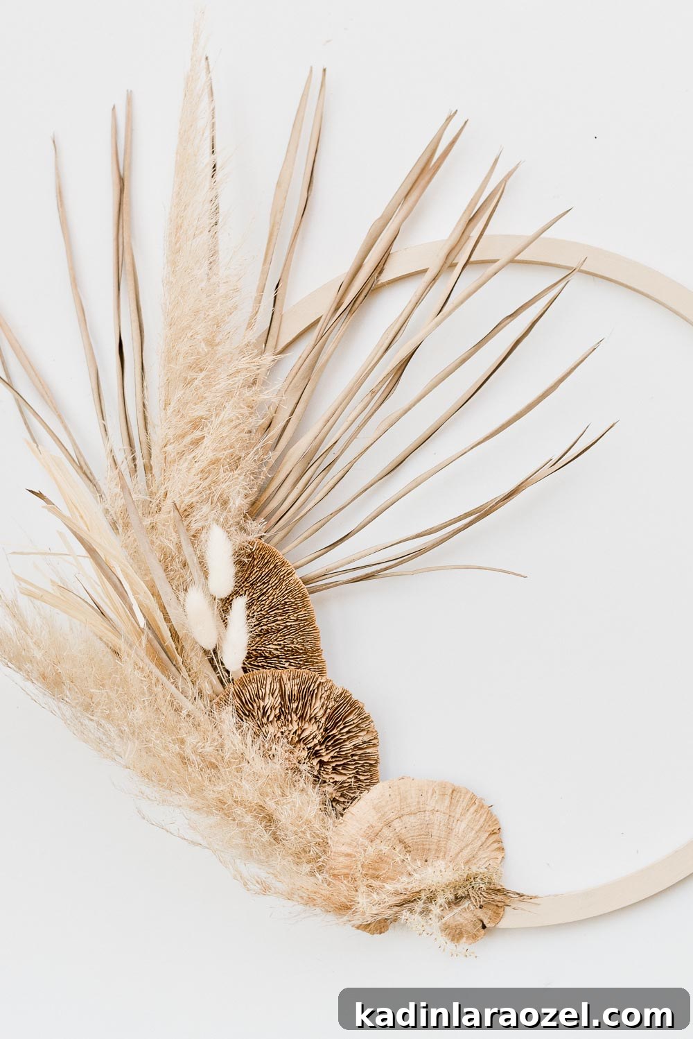 Image of an asymmetrical fall wreath made of pampas grass, wheat, and palm leaves.