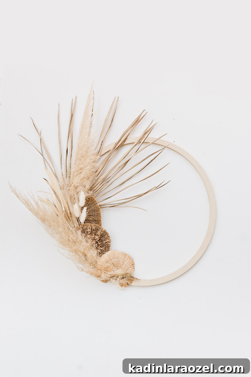 An asymmetrical fall wreath made of pampas grass, wheat, and palm leaves.