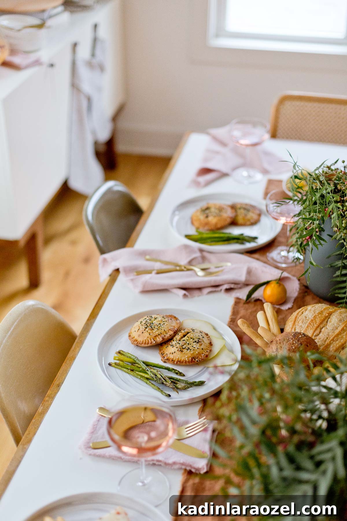 Overhead shot of holiday entertaining dining table with hand pies, asparagus, and wine.