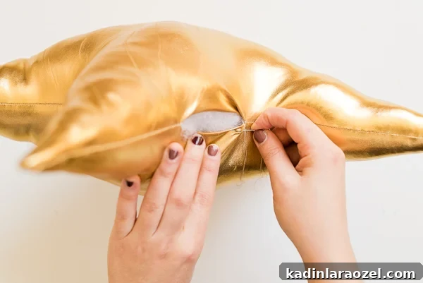 Sewing up the last part of a star pillow in gold metallic fabric