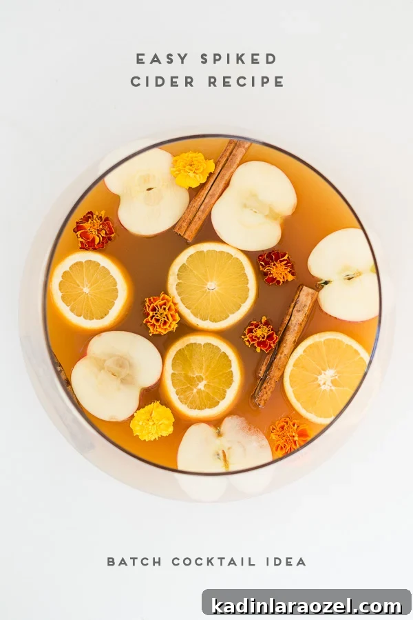 Easy spiked cider recipe in a punch bowl with sliced oranges and apples