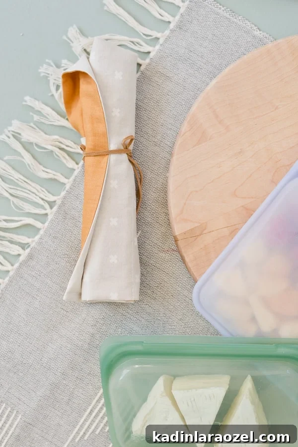 Fabric utensil roll closeup with other kitchen items on table.