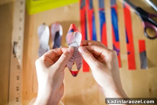 Person making a paper bow for a present out of recycled magazine scraps
