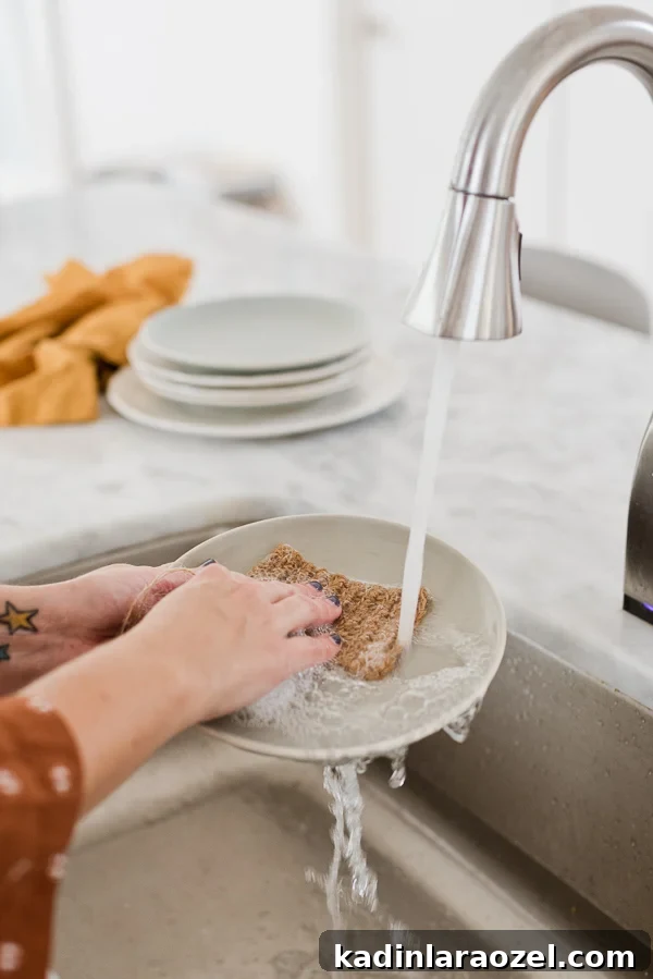 Running water over a dish in the sink, using a natural jute dish scrubber.