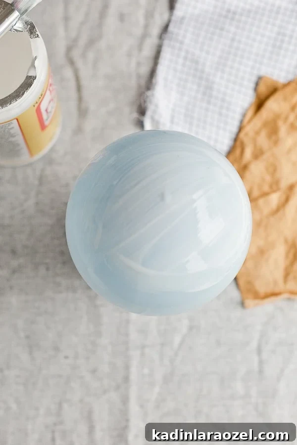 Mod podge on a blue balloon ready for paper mâché alternative craft.