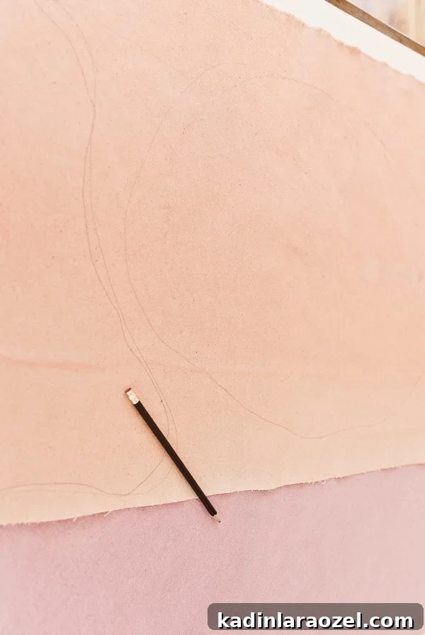 Drawing shapes with pencil onto pink and peach canvas.