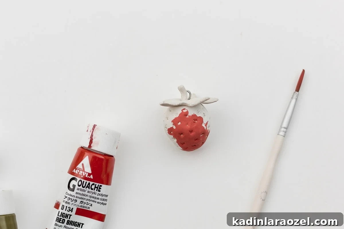 Painting clay strawberries with a small paintbrush.