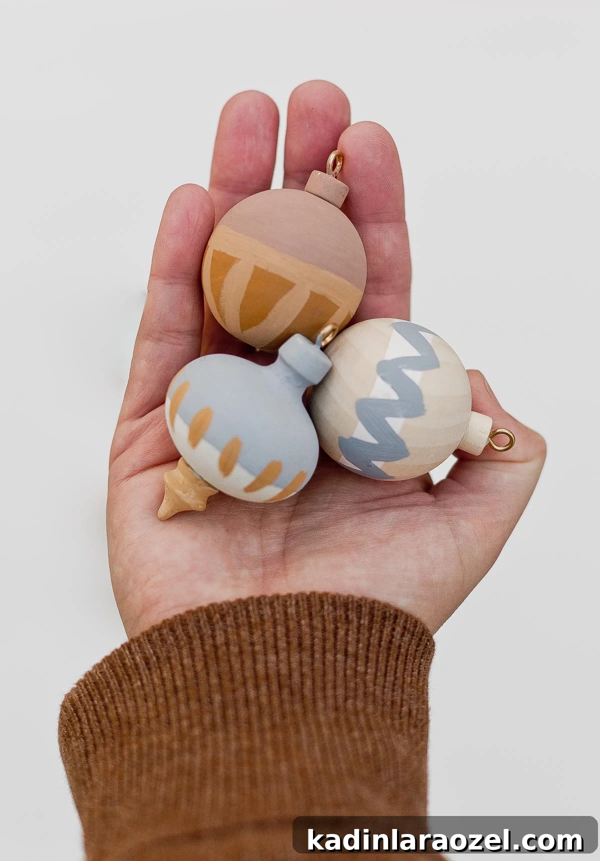 DIY Painted Wood Ornaments and Gift Toppers Tutorial 4 Holding DIY painted wood ornaments in the hand.