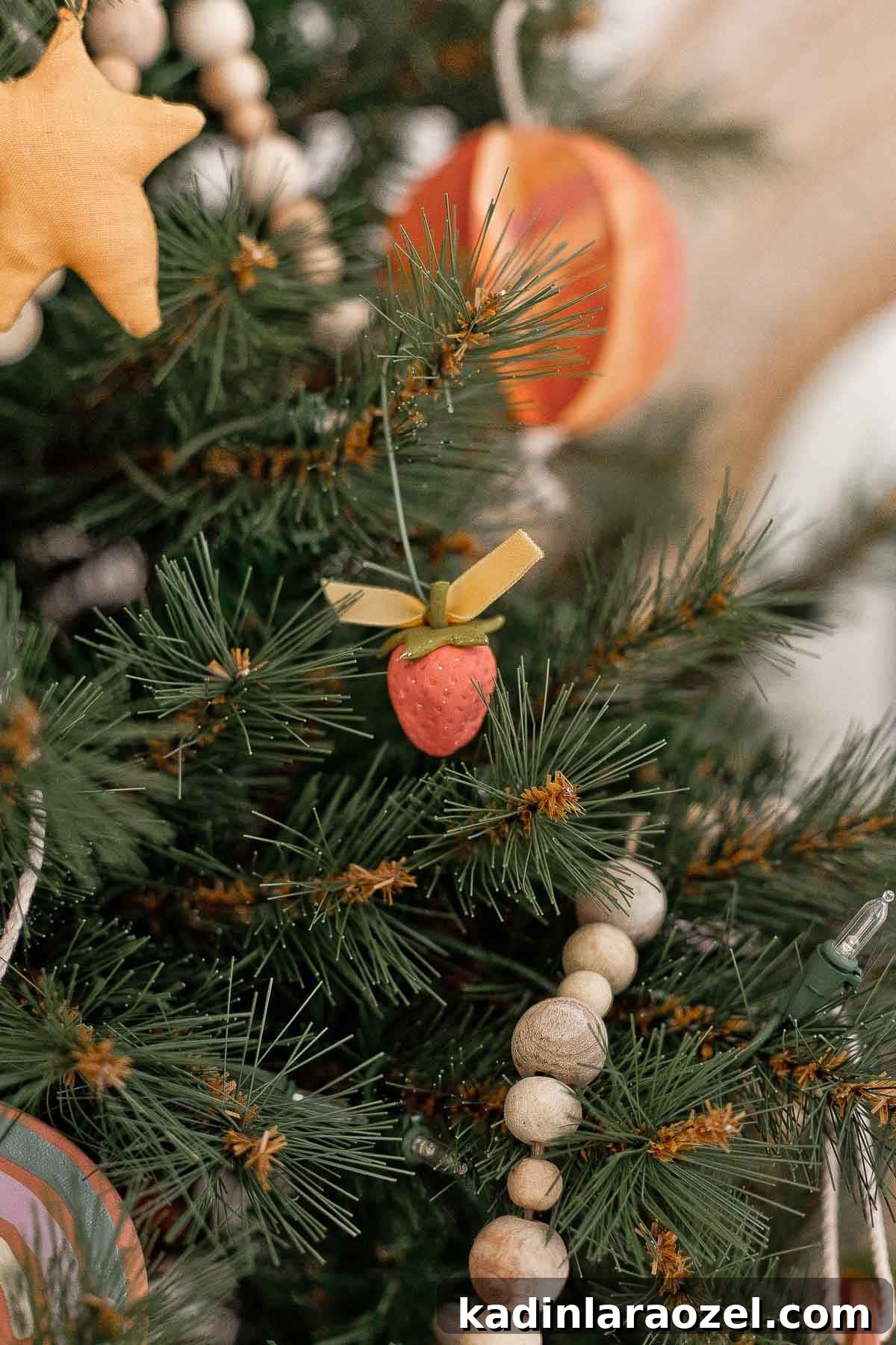 Handmade clay strawberry ornaments on a Christmas tree.