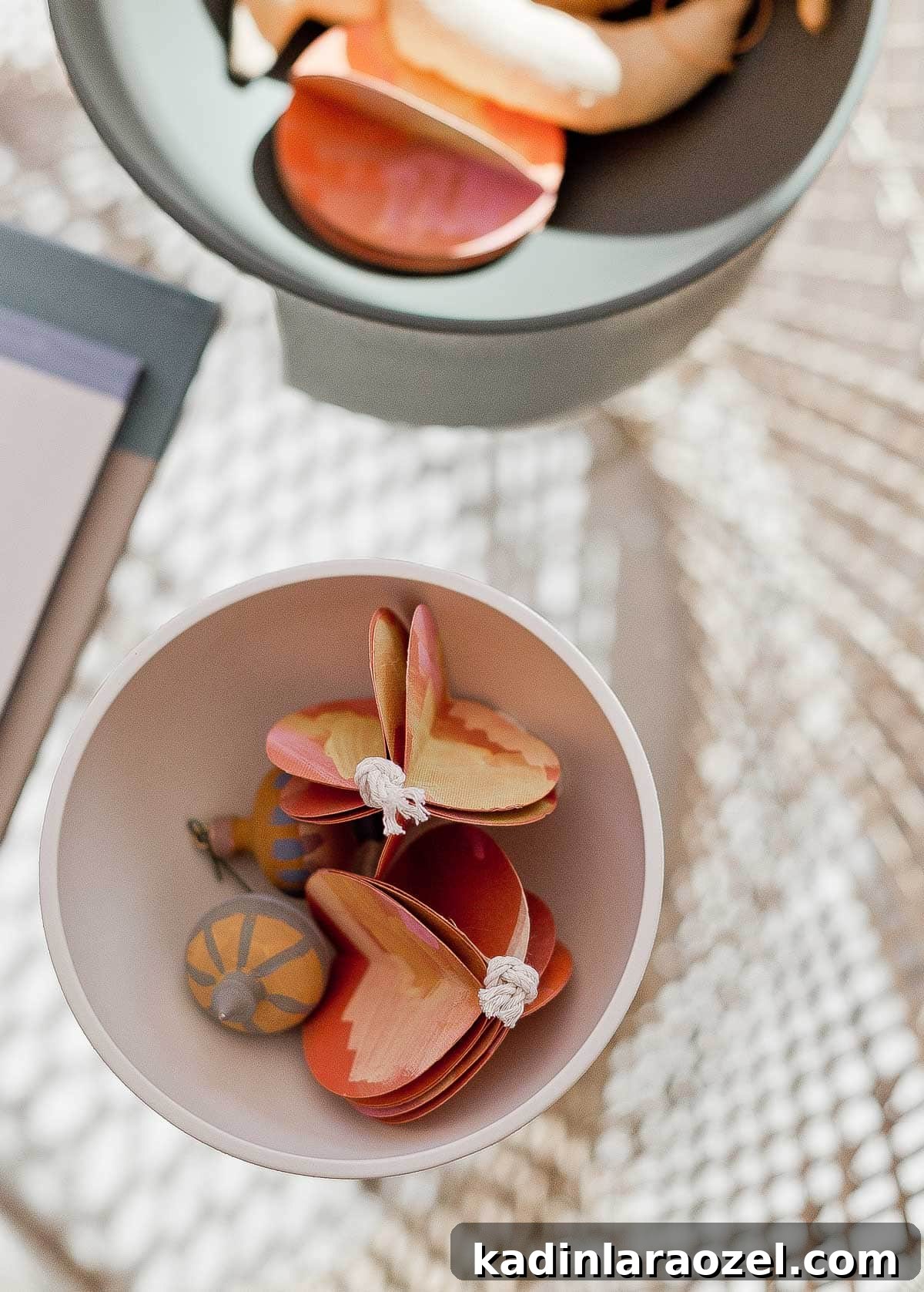 Handmade ornaments in a modern bowl on a glass coffee table.