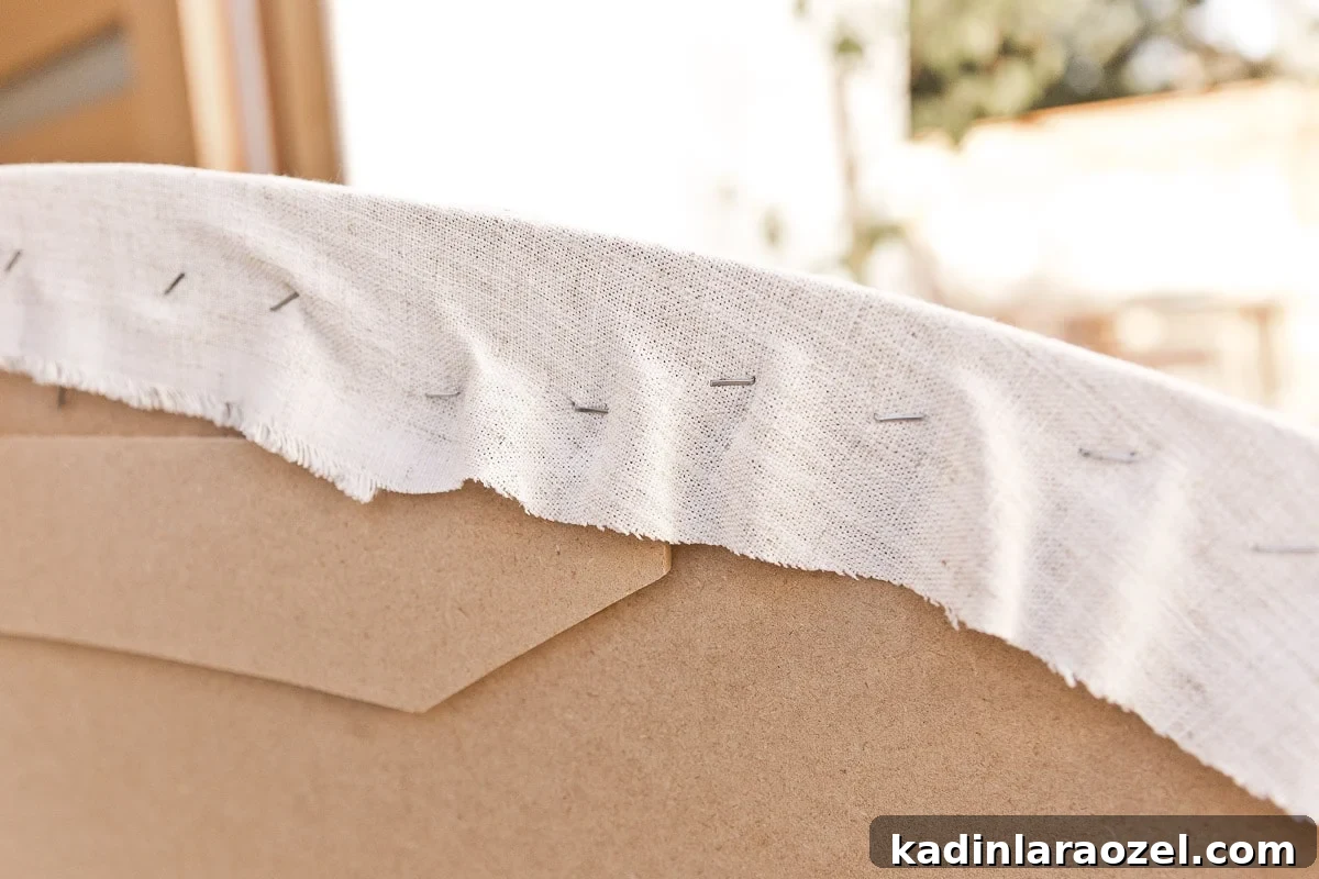Statement-Making DIY King Size Half-Circle Headboard 11 Closeup photo of stretching fabric over MDF panels and stapling to the back.