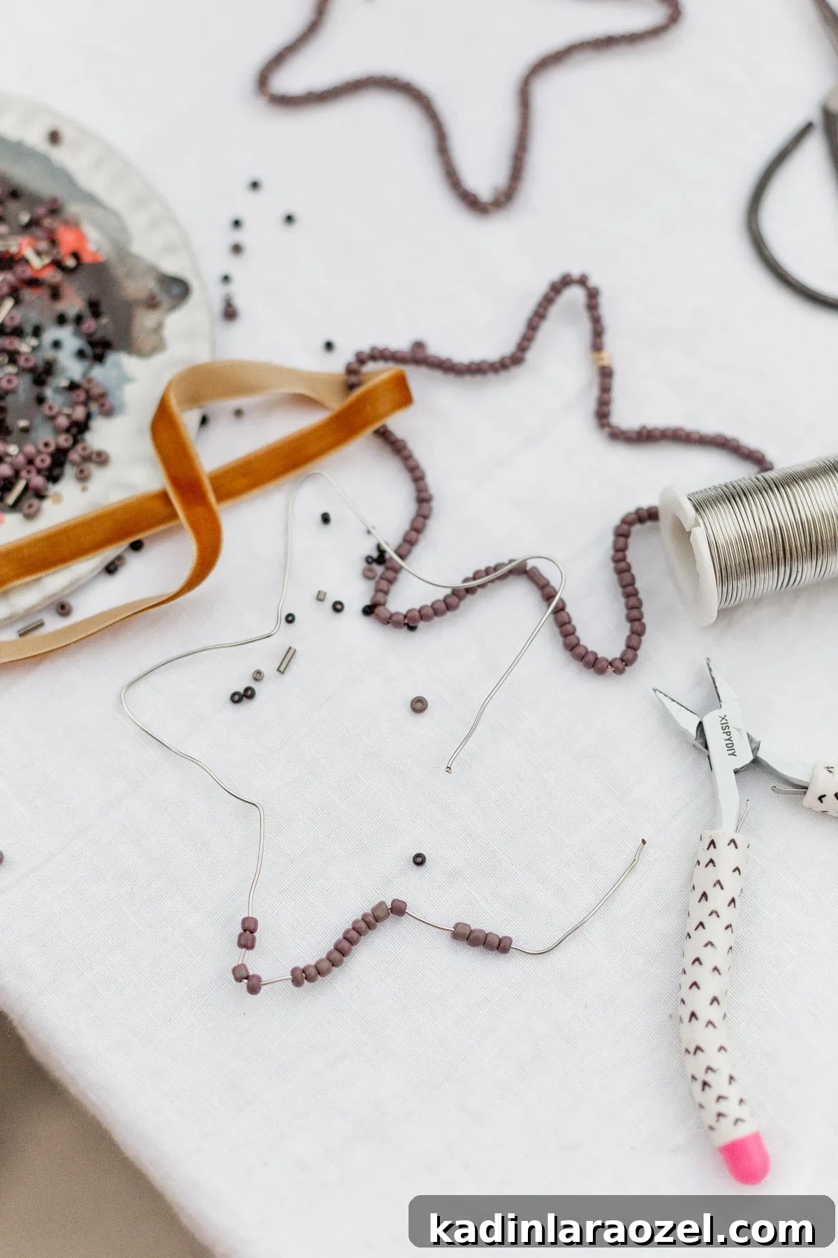 DIY Beaded Christmas Ornaments: Step-by-Step Holiday Craft Guide 3 Purple beaded ornaments, shaped like stars, being made on a white table.