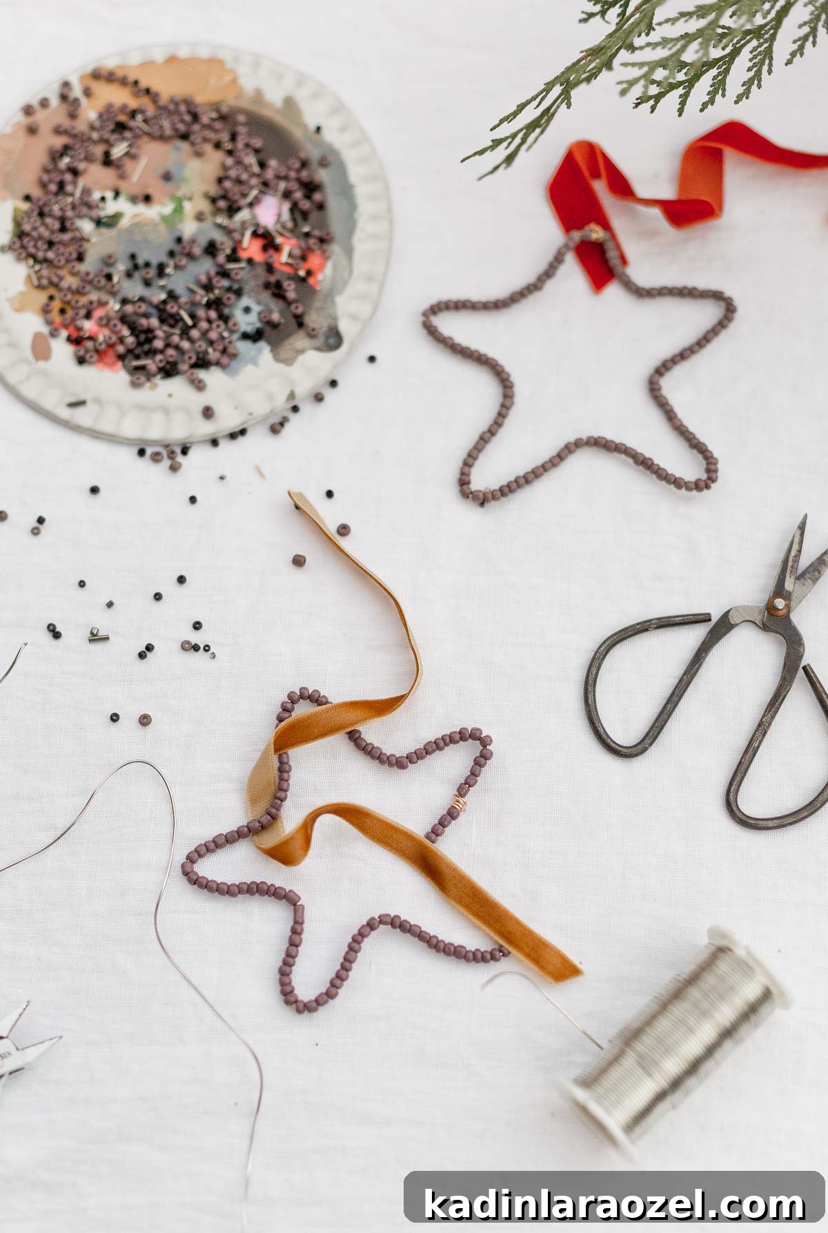 DIY Beaded Christmas Ornaments: Step-by-Step Holiday Craft Guide 7 Beaded star ornaments on a white table cloth with craft supplies.