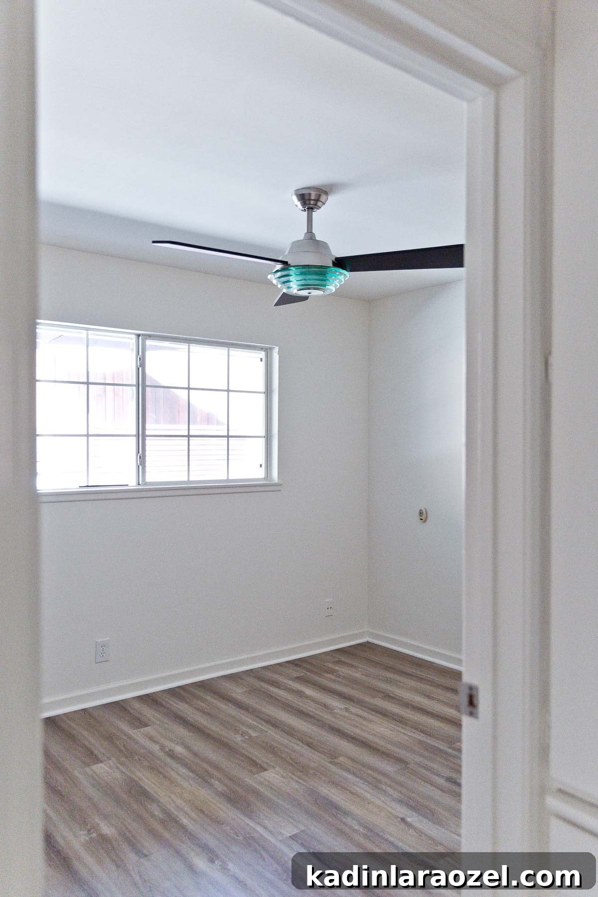 Photo of small, empty bedroom with ceiling fan.