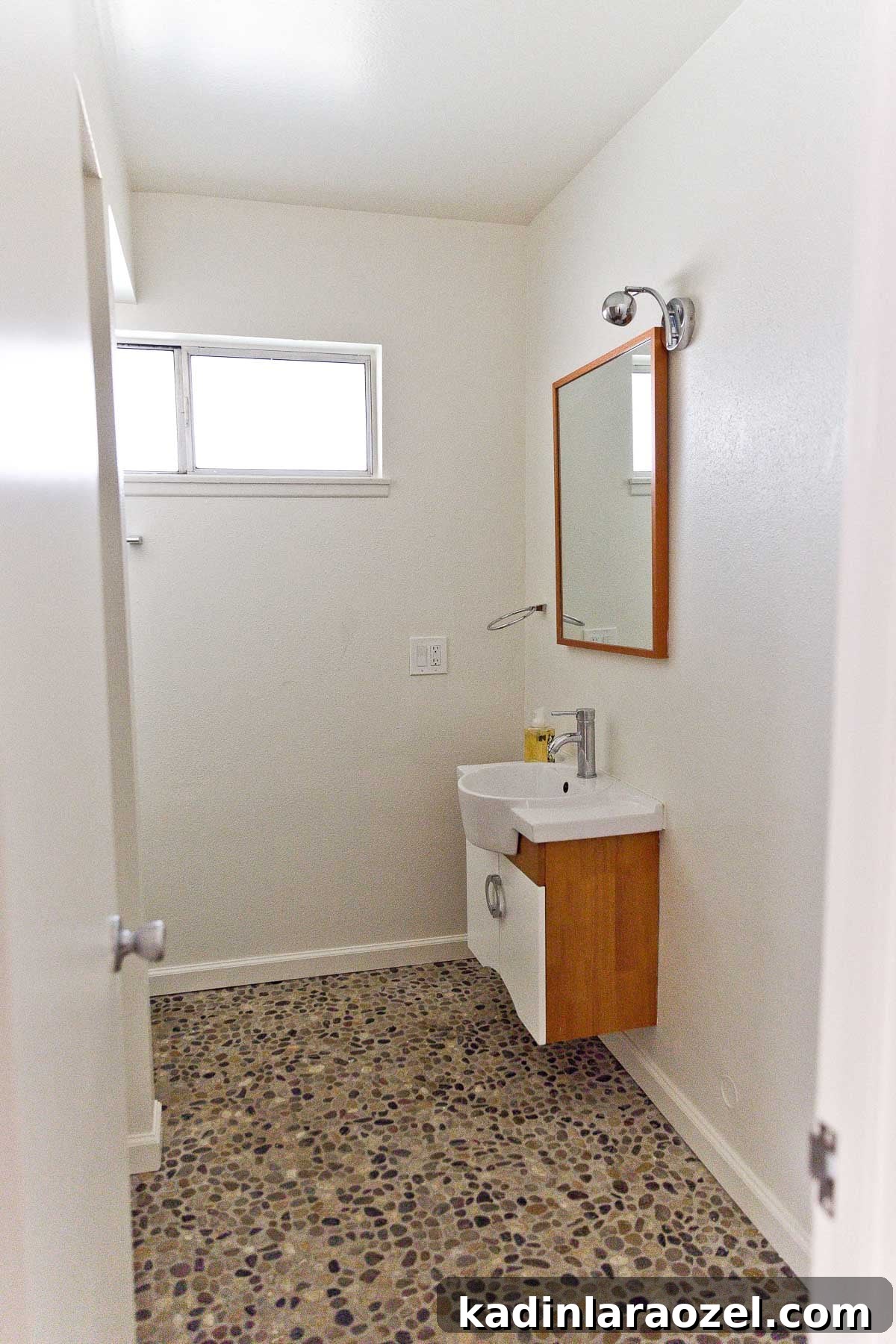Photo of river rock flooring in empty bathroom.