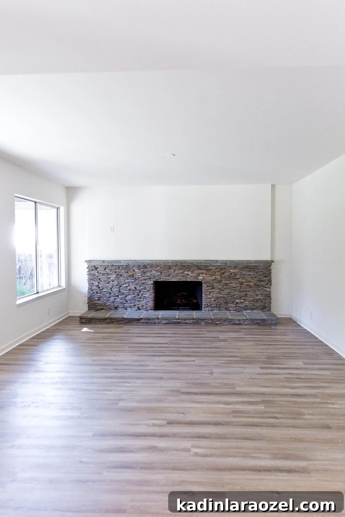 Photo of empty living room with statement ledger rock fireplace.